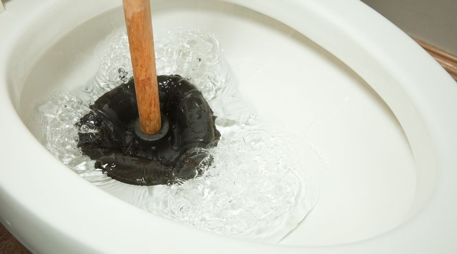 Plunger in toilet bowl with water ripples, highlighting plumbing issues for Air Works Heating & Air HVAC services.