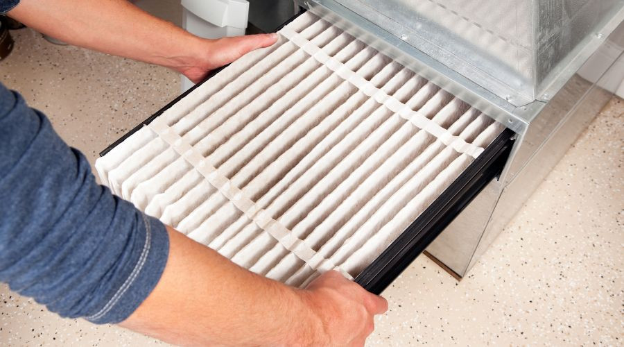 Person's hands inspecting a clean air filter and housing for HVAC maintenance by Air Works Heating & Air.