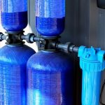 Two large blue tanks with pipes and filters for water purification at Air Works Heating & Air HVAC services.
