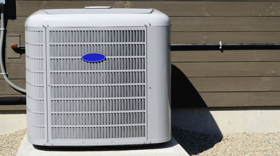 Air conditioning unit positioned beside a wooden wall, highlighting the importance of AC maintenance and repair services.