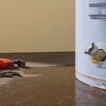 Water heater with visible corrosion and rust, alongside plumbing tools, indicating potential leaks and the need for replacement, relevant to water heater installation services in Franklinton, NC.